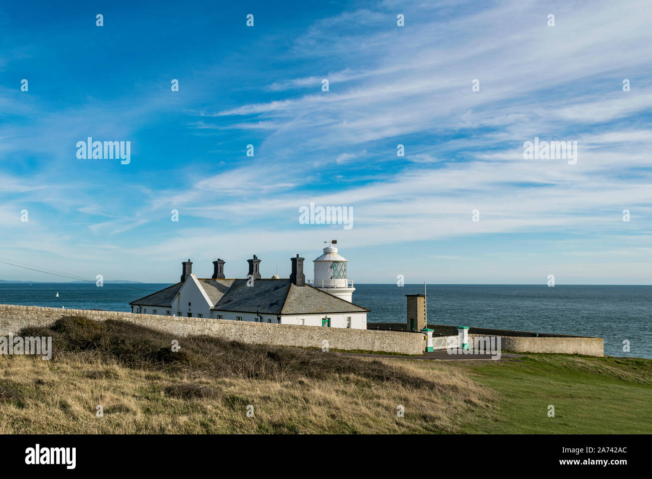 Behind Anvil Point lighthouse looking out to sea on the jurassic coast with blue sky, Swanage, Dorset Stock Photo