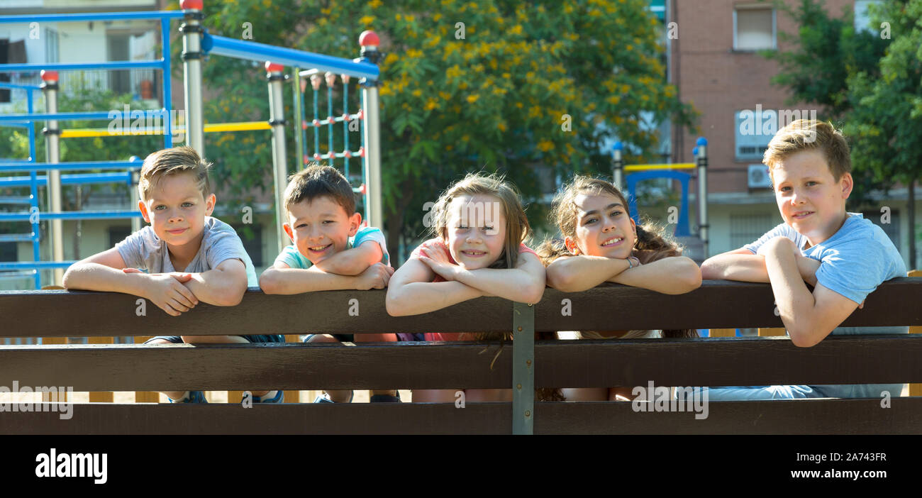 Glad children sitting on a bench at the playground Stock Photo - Alamy
