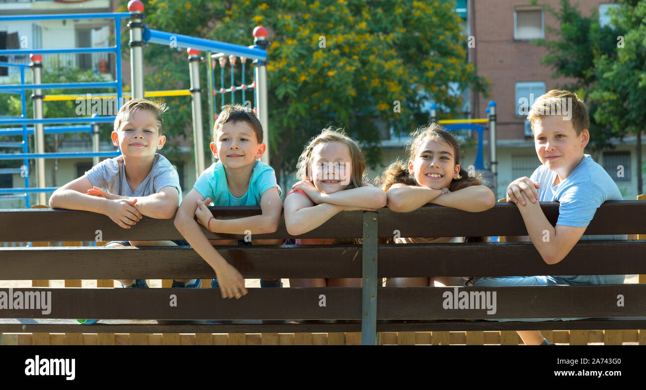 Glad children sitting on a bench at the playground Stock Photo - Alamy