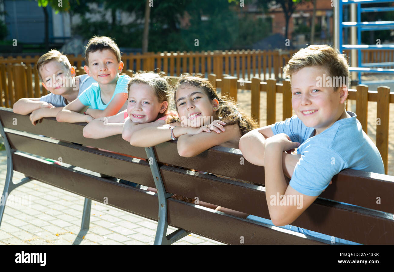 Glad children sitting on a bench at the playground Stock Photo - Alamy