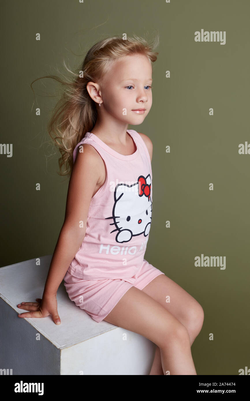 Brooding beautiful girl sitting on a white cube and posing, school ...