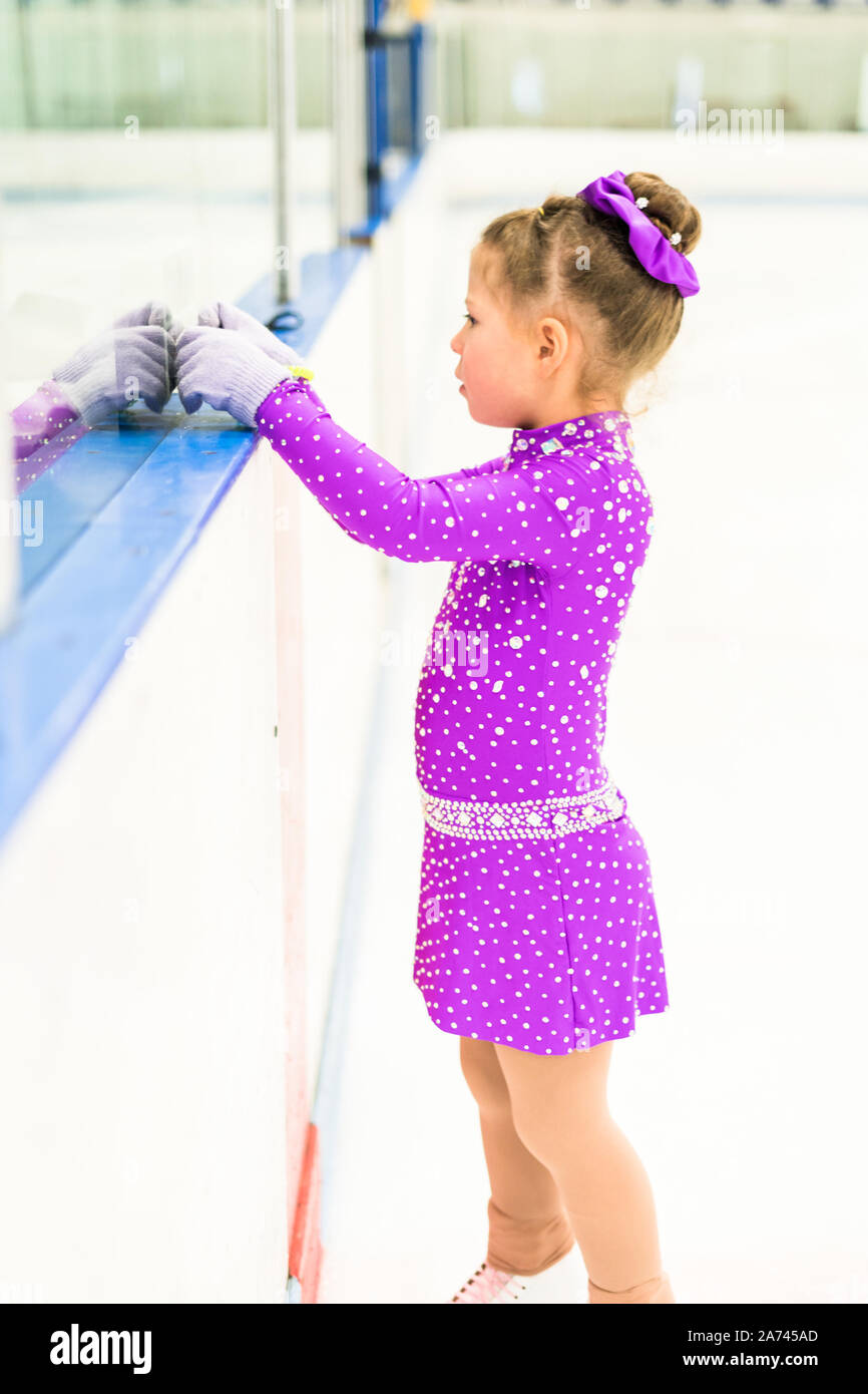 Little girl practicing figure skating in a purple dress with crystals