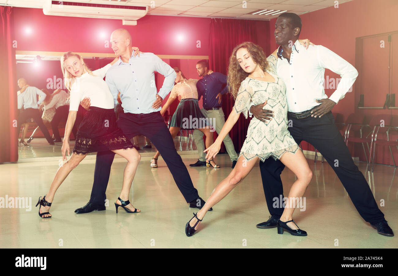 Young smiling people practicing passionate samba in dance class Stock Photo