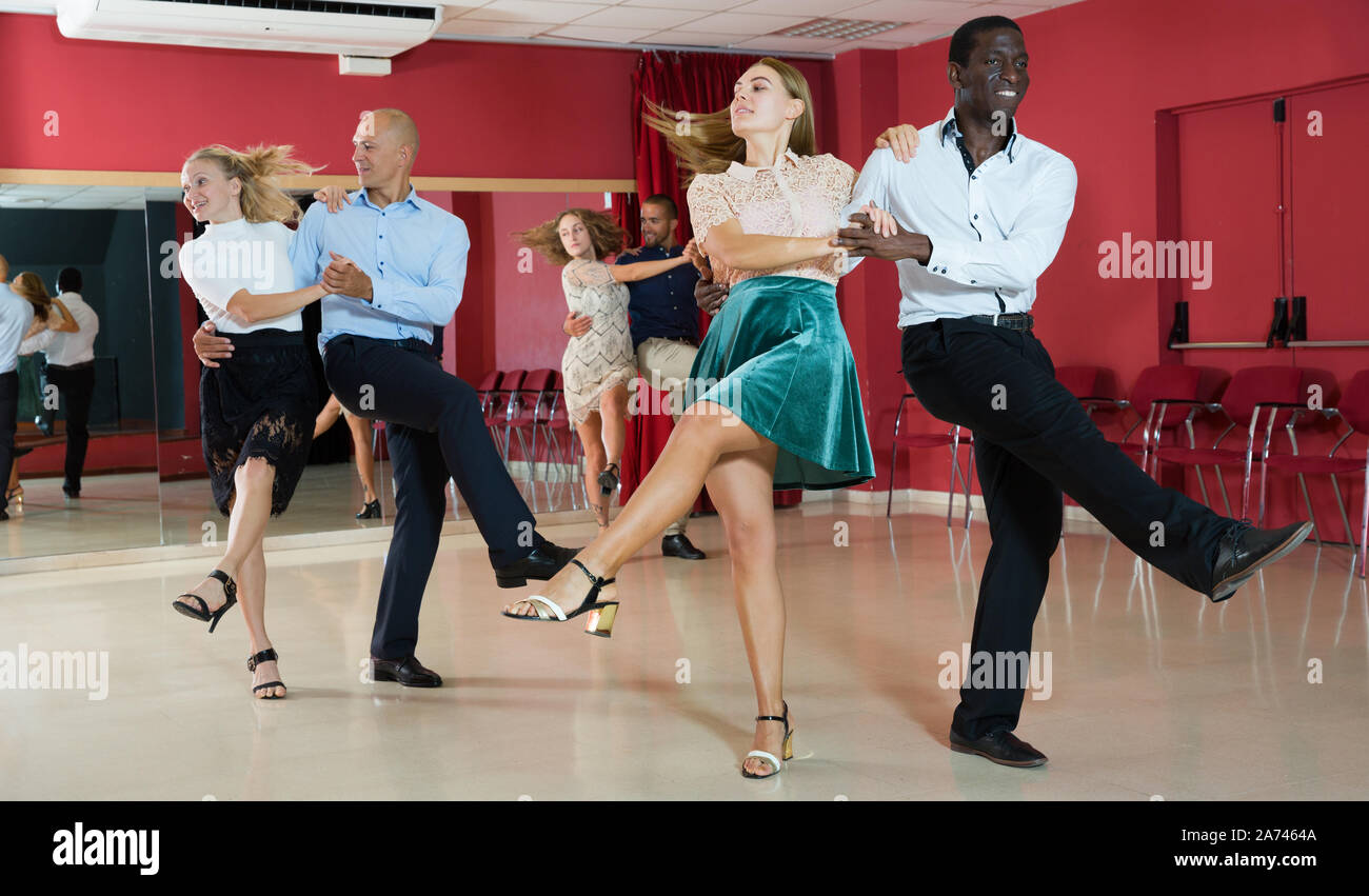 Young smiling people practicing vigorous jive movements in dance class Stock Photo