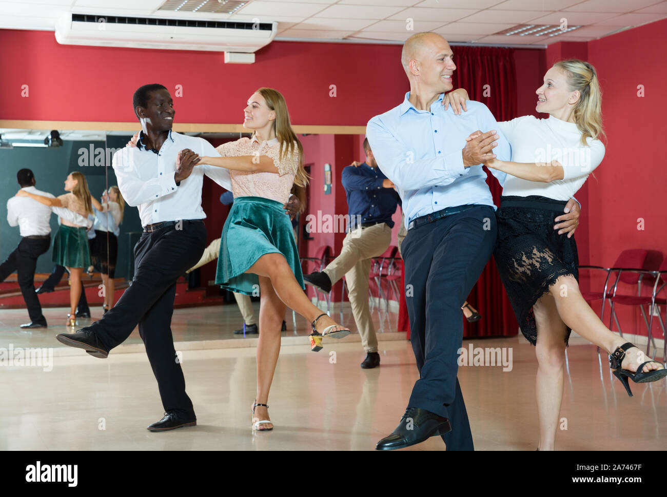 Young smiling people practicing vigorous jive movements in dance class Stock Photo