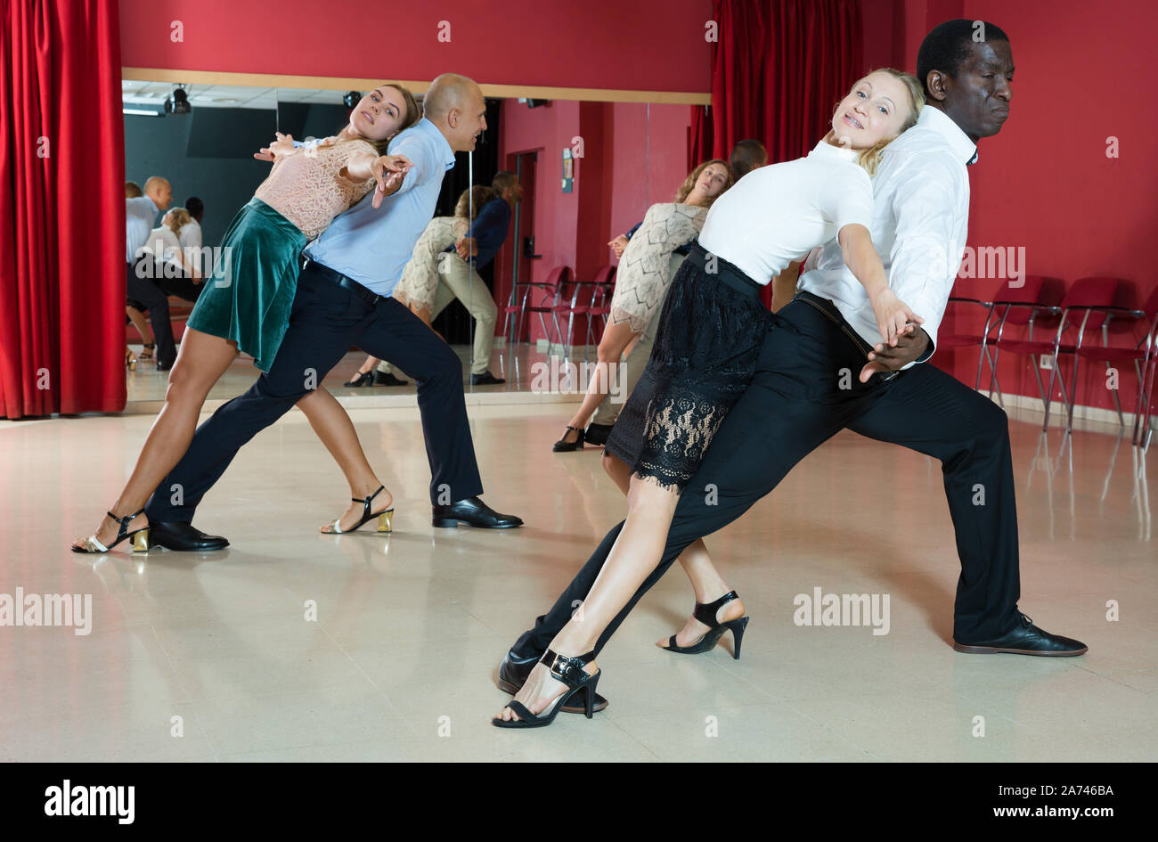 Young smiling people practicing passionate samba in dance class Stock Photo