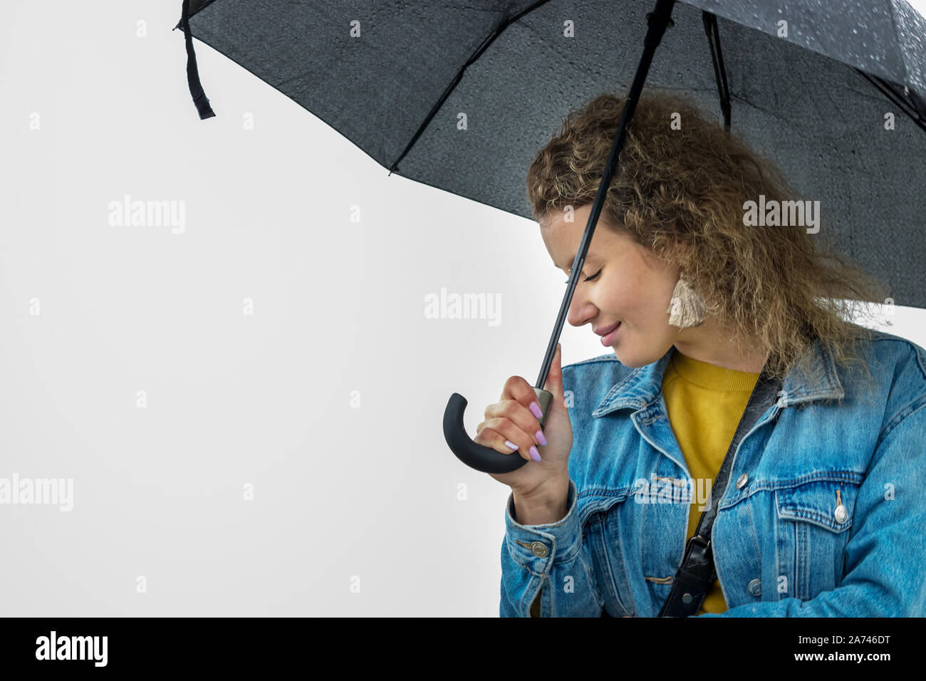 Portrait of a young woman with curly hair holding an umbrella. Stock Photo