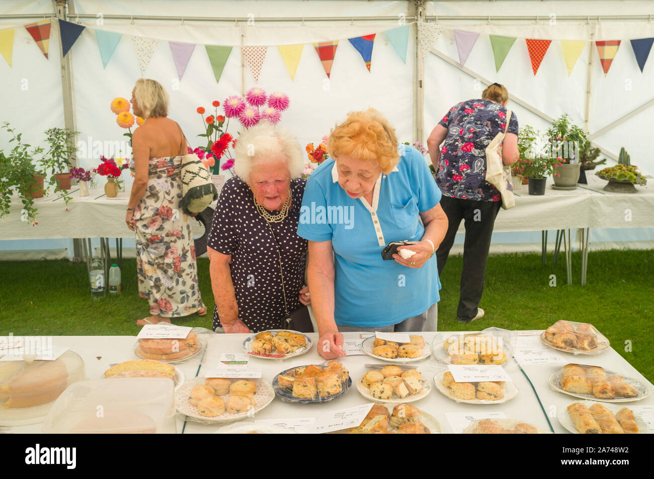 Two ladies inspect the scones in the flower tent at the village horticultural show Stock Photo