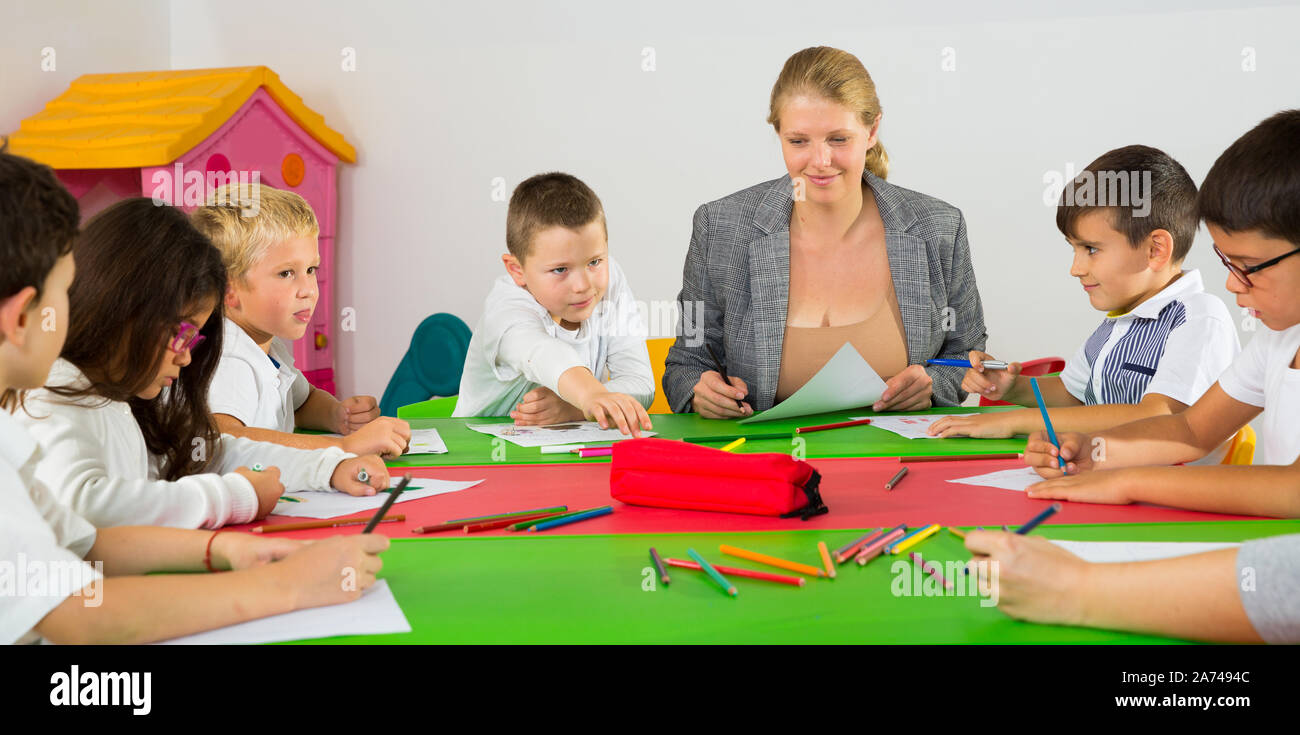 Cute schoolchildren drawing with teacher in classroom Stock Photo - Alamy