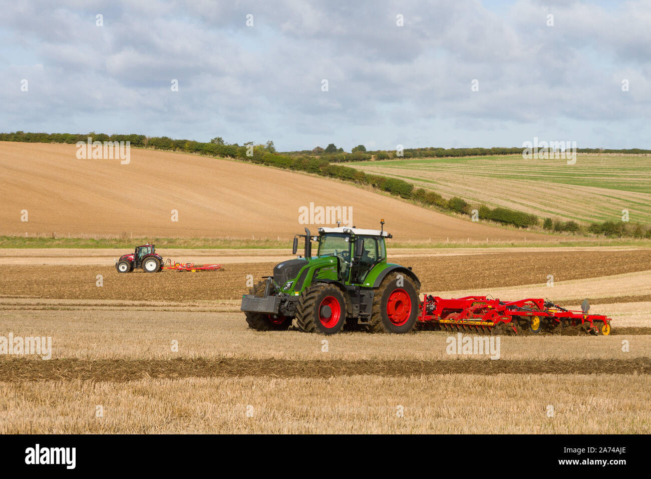 A large modern green Fendt tractor cultivating fields at a ploughing match near Ipsden on the edge of the Chilterns with blue sky and Cumulus clouds Stock Photo