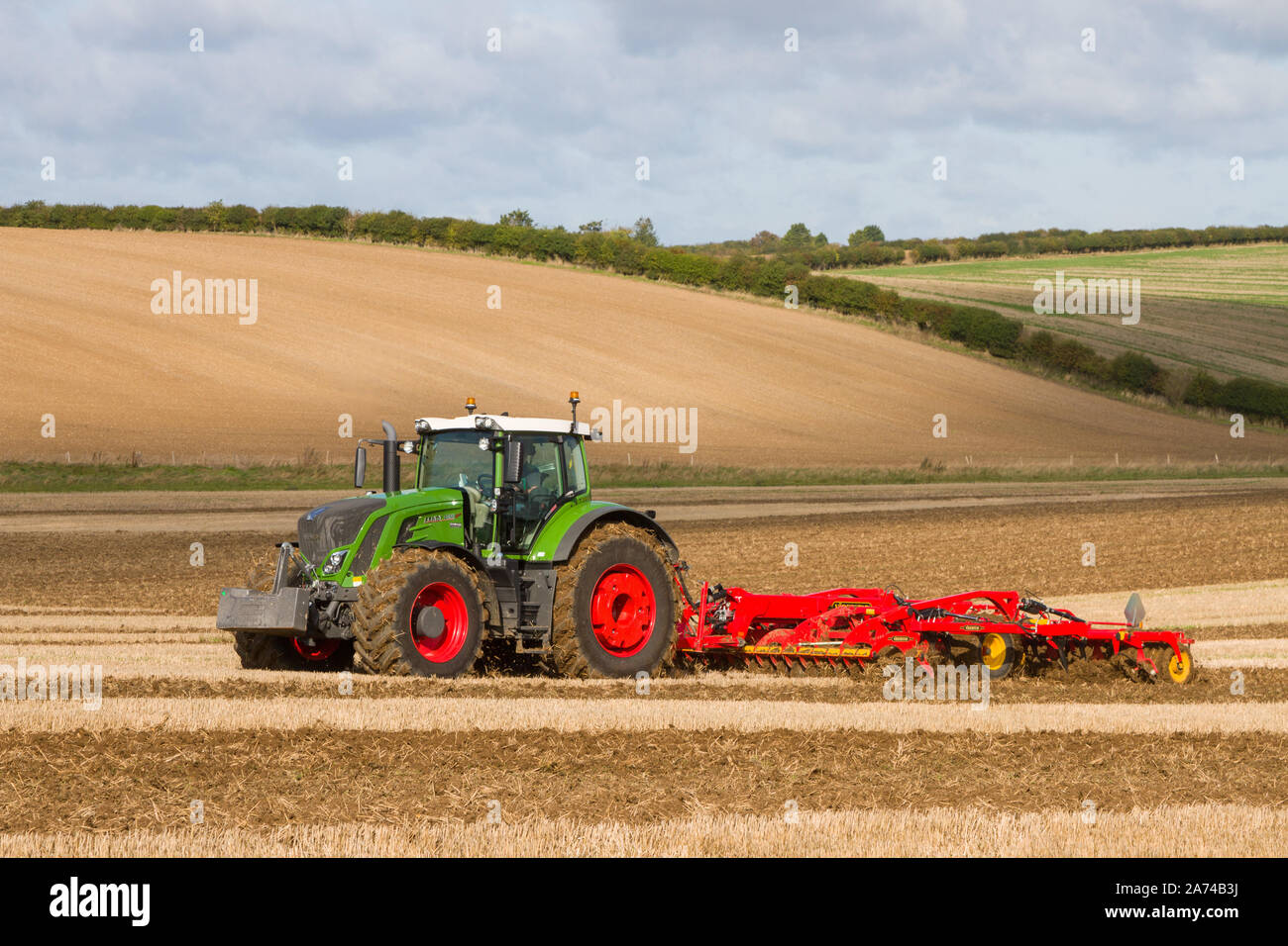 A large modern green Fendt tractor cultivating fields at a ploughing match near Ipsden on the edge of the Chilterns with blue sky and Cumulus clouds Stock Photo