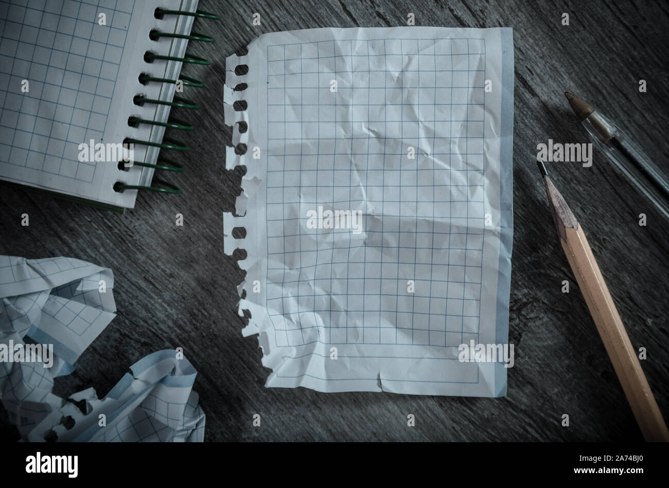 Crumpled empty pages and notebook lying on wooden surface Stock Photo