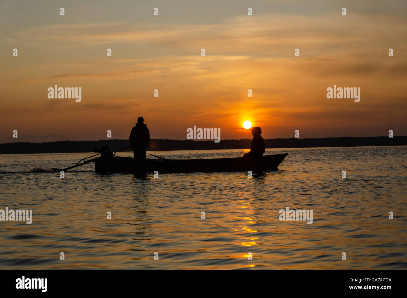 Silhouette of fishing boat and fisherman in the sunrise on the lake in ...