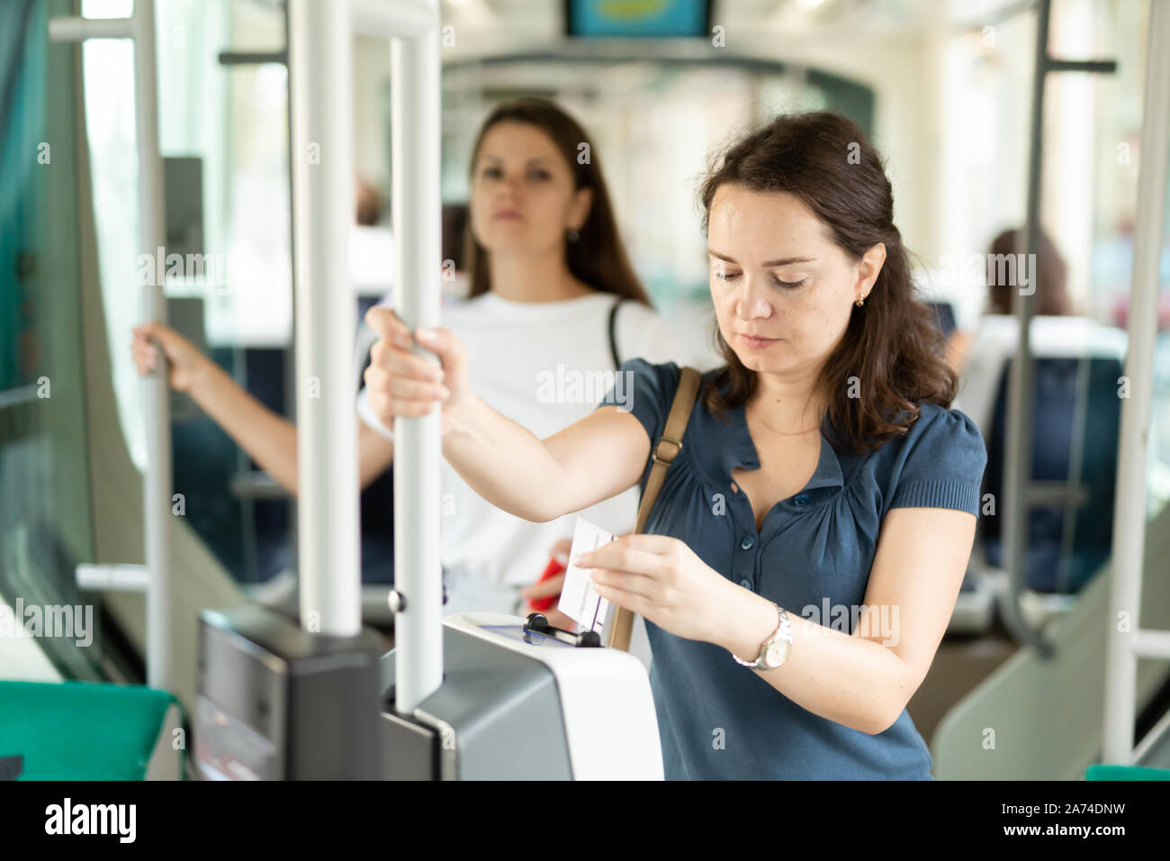 Young woman inserting ticket in modern punching machine, validating ...