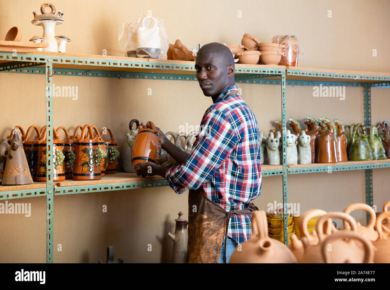 Afroamerican artisan in apron having ceramics in store warehouse Stock Photo Alamy