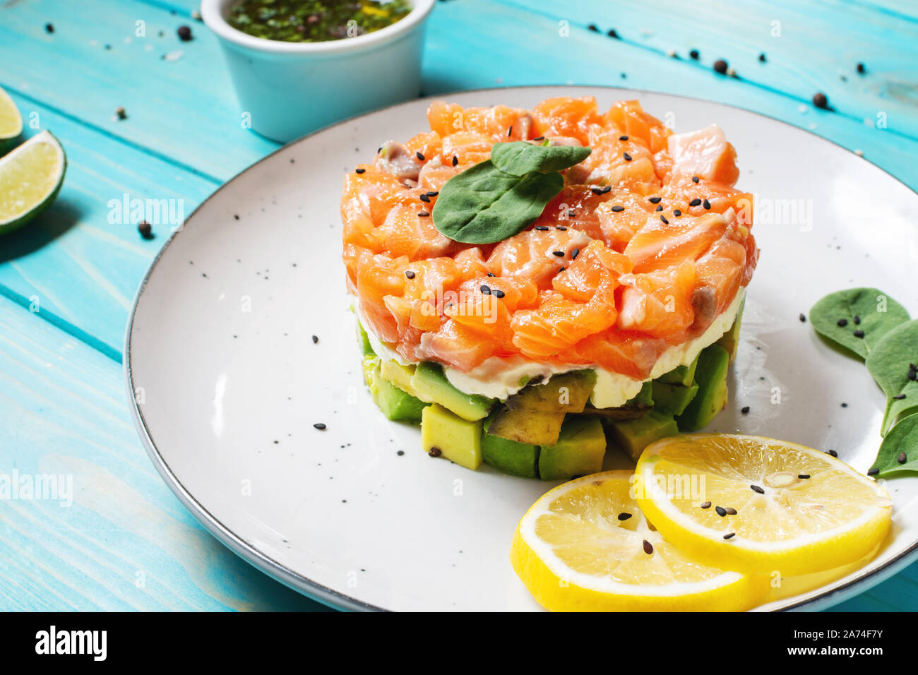 Delicious avocado and salted salmon tartar on blue wooden background ...