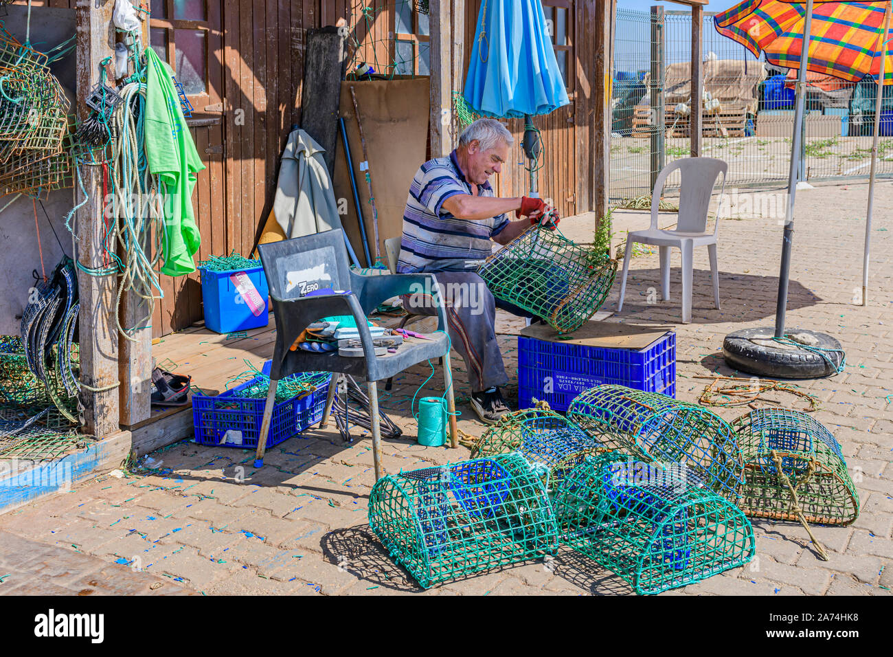 Local fisherman repairing fixing mending octopus nets traps pots trap pot net, Santa Luzia, East Algarve, Portugal. Stock Photo