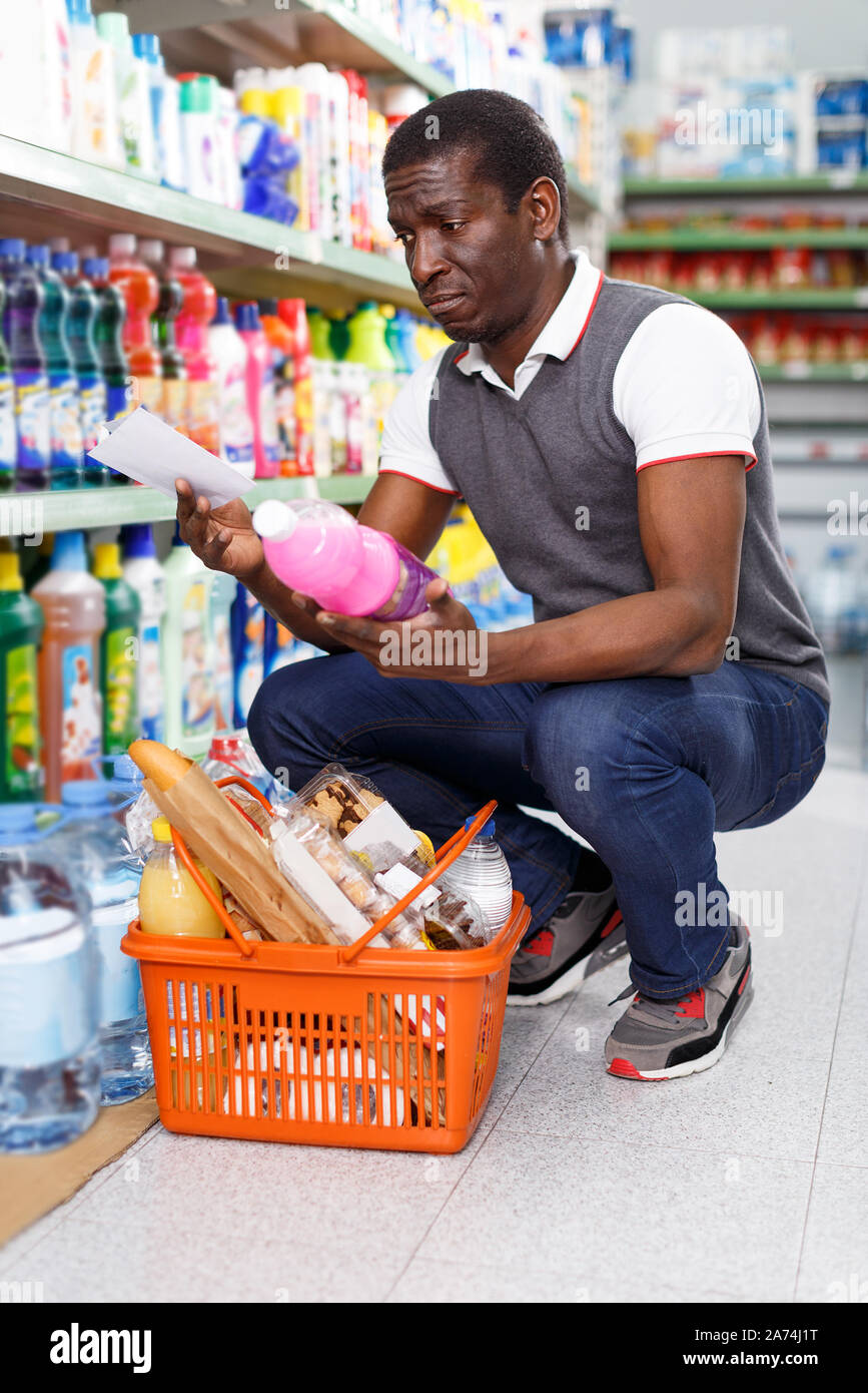 Ordinary African man holding list of goods and shopping in supermarket ...