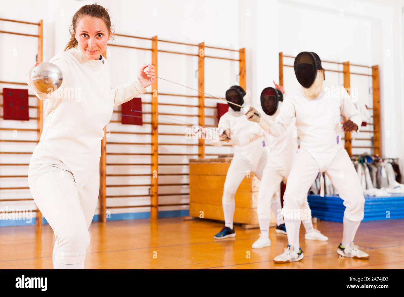 Sporty young female fencer practicing fencing technique in training