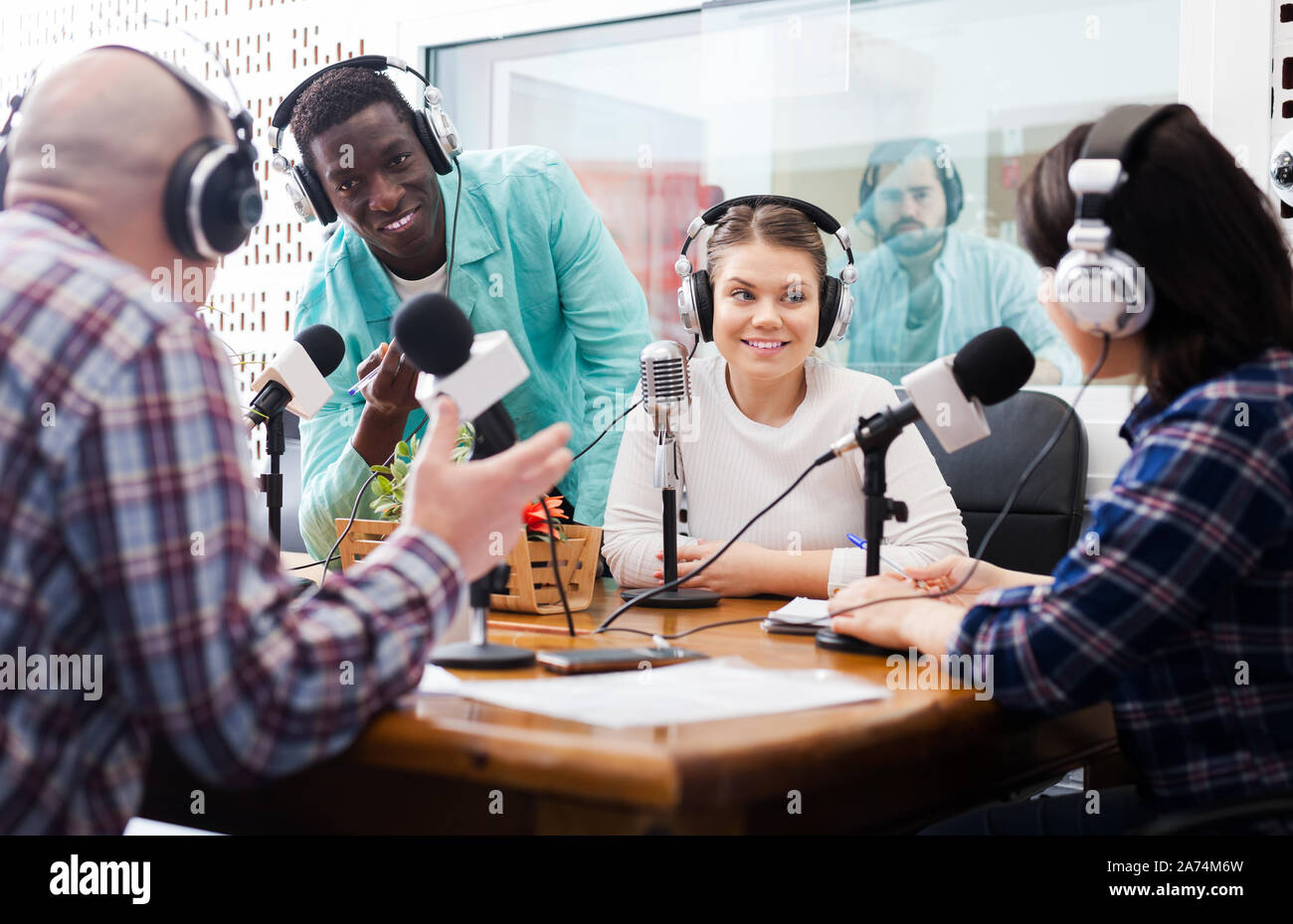 Positive male and female radio hosts talking with guest in sound ...