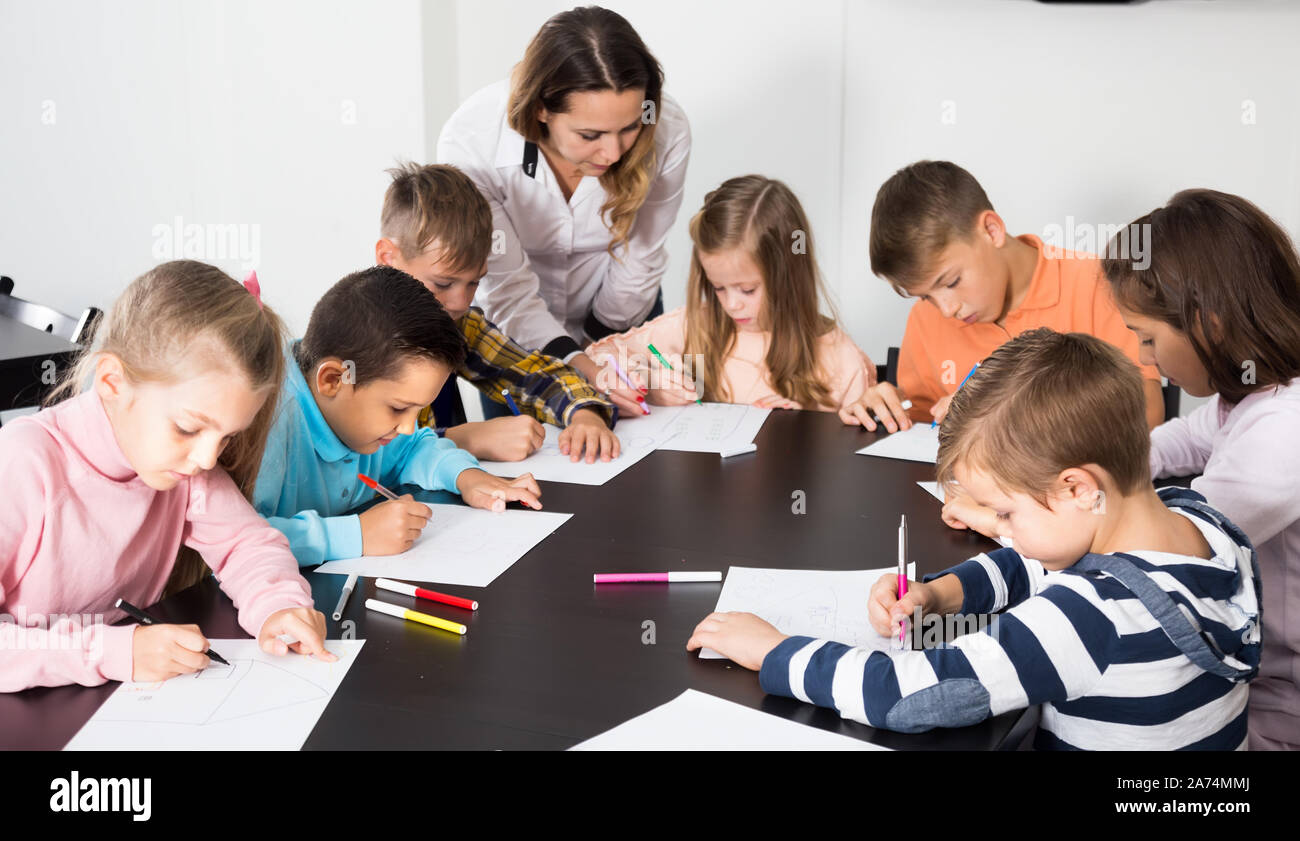 Teacher and elementary age kids drawing at classroom in school Stock ...