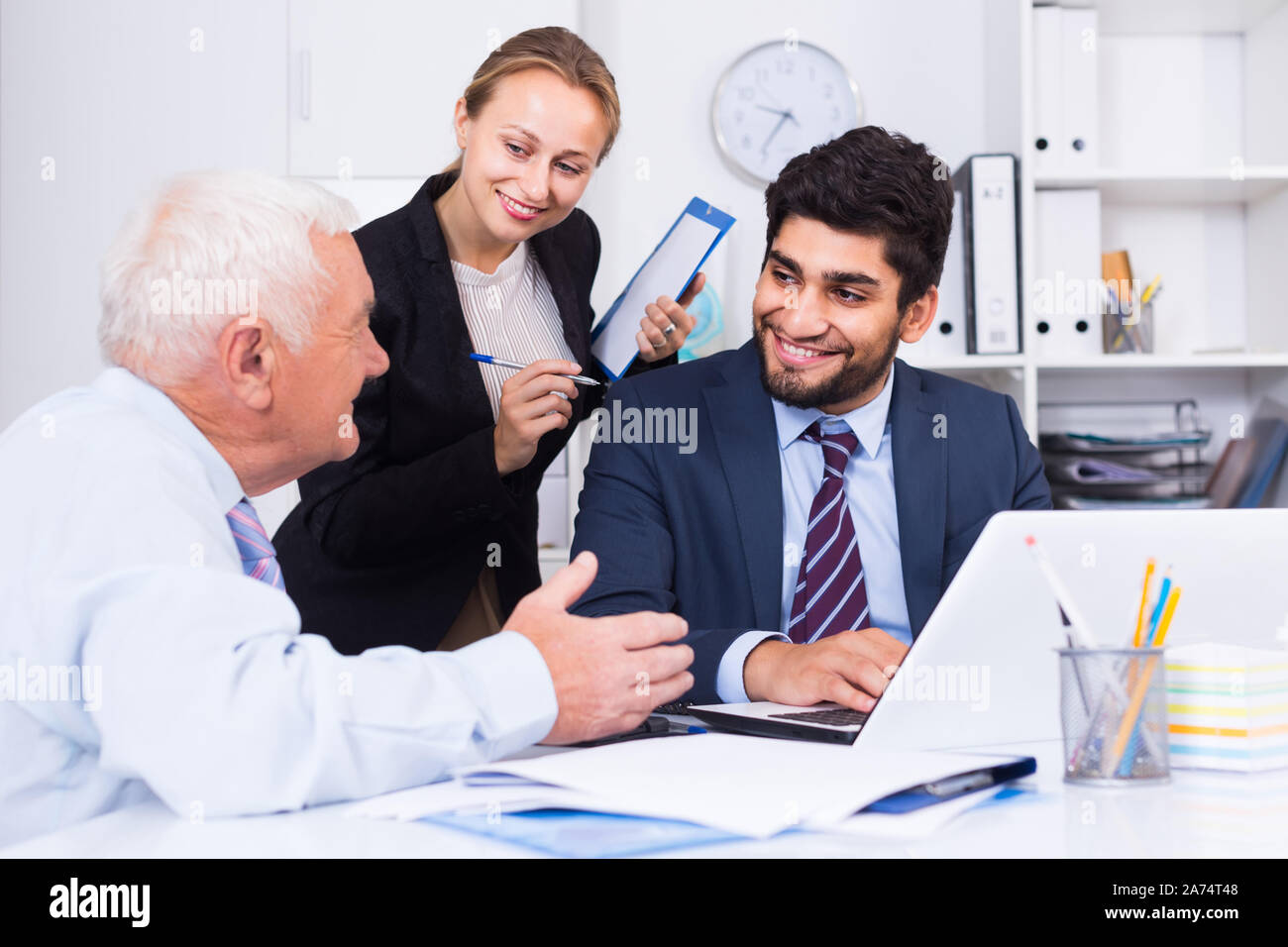 Mature male is talking to colleague, while the secretary writing ...