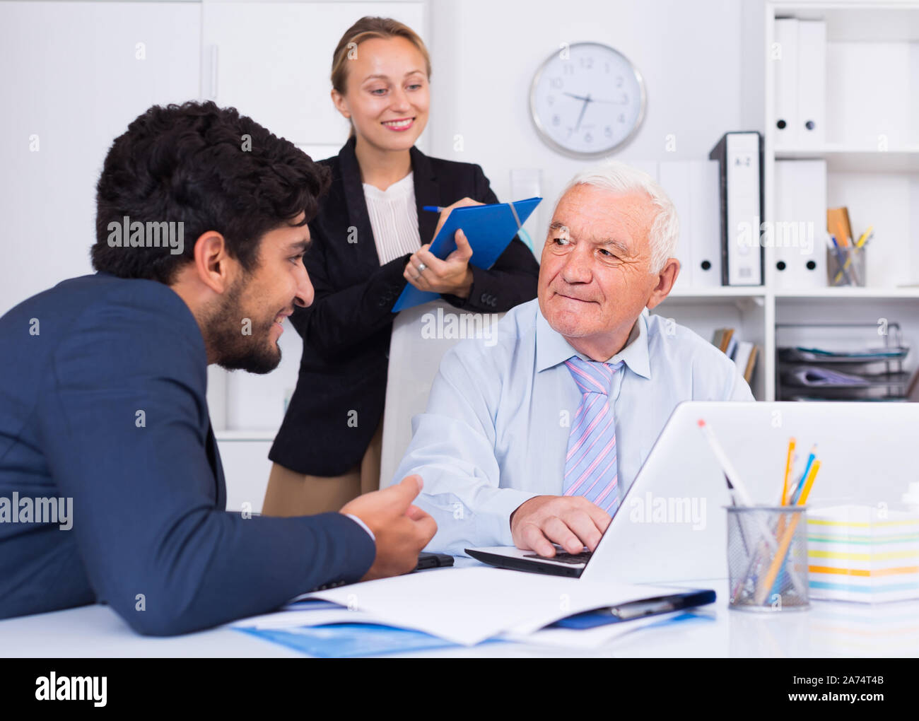 Mature man is talking to colleague, while the secretary writing ...