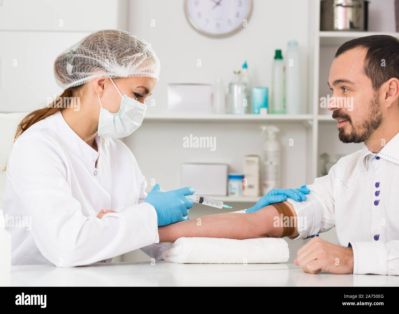 Young female nurse ready to make injection to male visitor in hospital ...