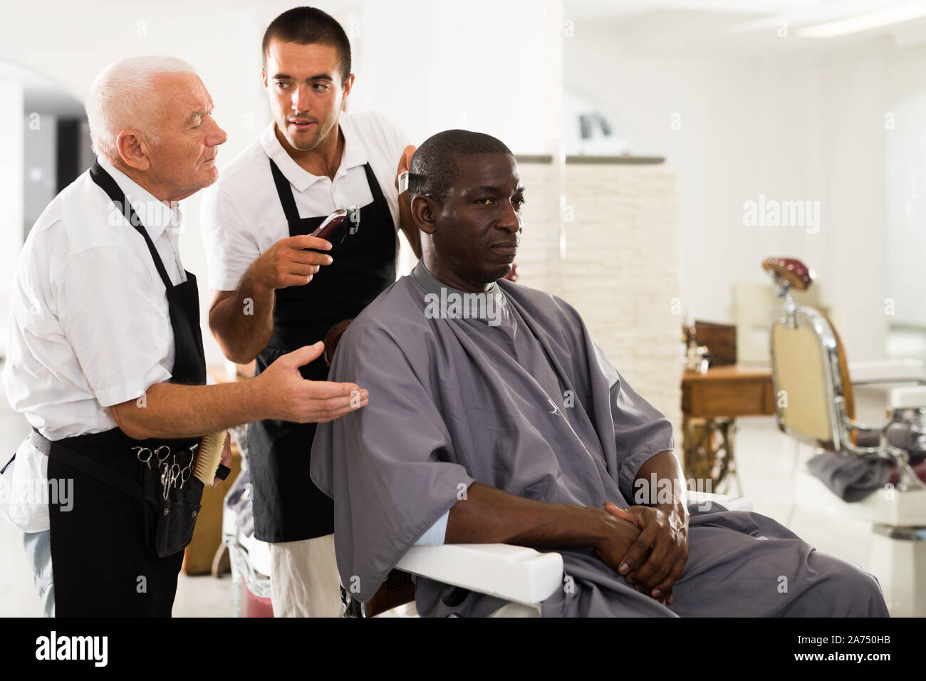 Training haircut. Experienced aged barber teaching apprentice to male  haircut in hair salon Stock Photo - Alamy