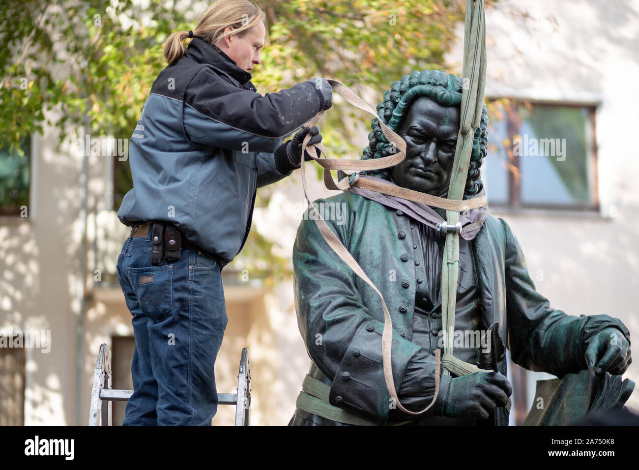 Eisenach, Germany. 30th Oct, 2019. The restorer Alexander Löwe attaches the restored Bach monument to sling ropes in order to lift it to its place in the women's plan with the help of a crane. The monument, designed by the sculptor Adolf von Donndorf, was erected in 1884 and was placed in front of the Bach-Haus am Frauenplan in 1938. Credit: Michael Reichel/dpa/Alamy Live News Stock Photo