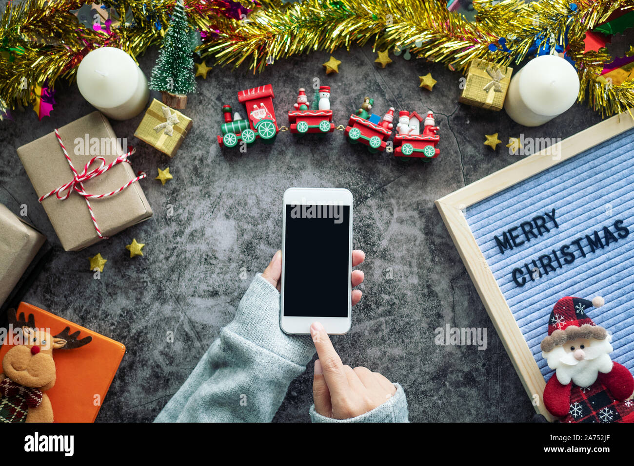 online shopping for Christmas season and gift festival. hand holding mobile phone with blank screen and press button for shopping online, decorations Stock Photo
