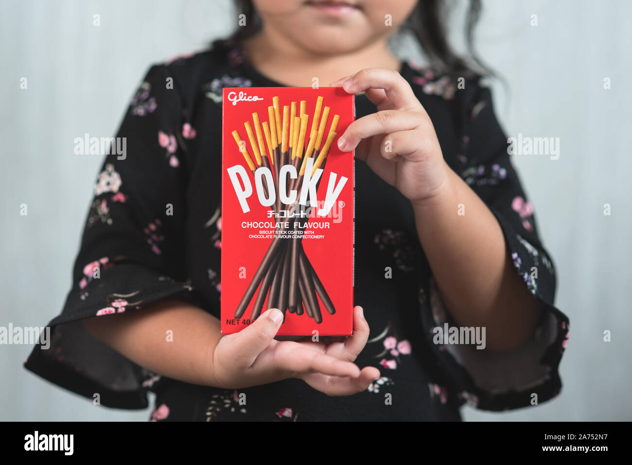 Petaling jaya, Selangor, Malaysia - 20 Oktober 2019 : Little asian girl holding a box of pocky brand of chocolate sticks. Pocky is a famous confection Stock Photo