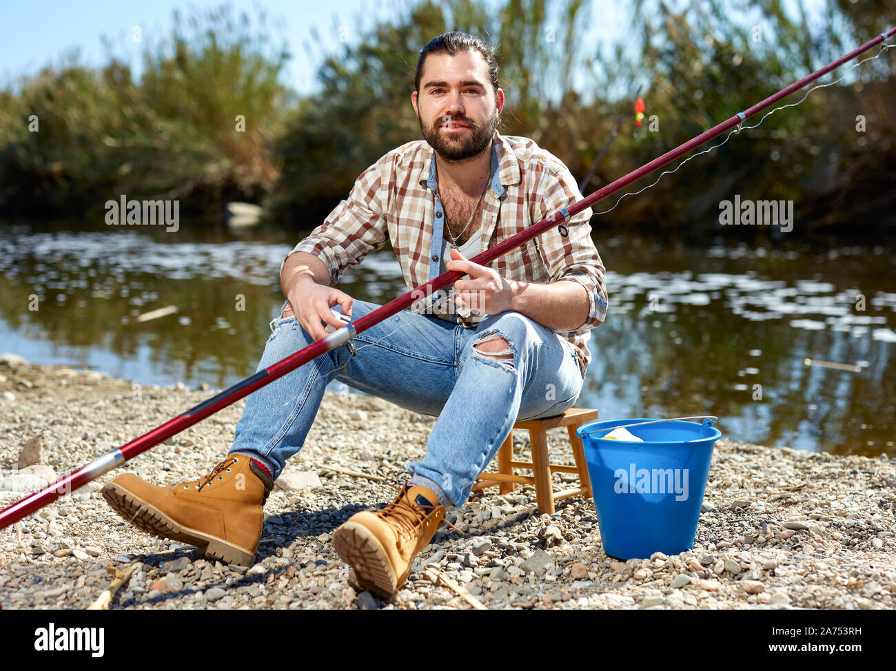 Adult male fisherman pulls fishing line on a fishing rod Stock