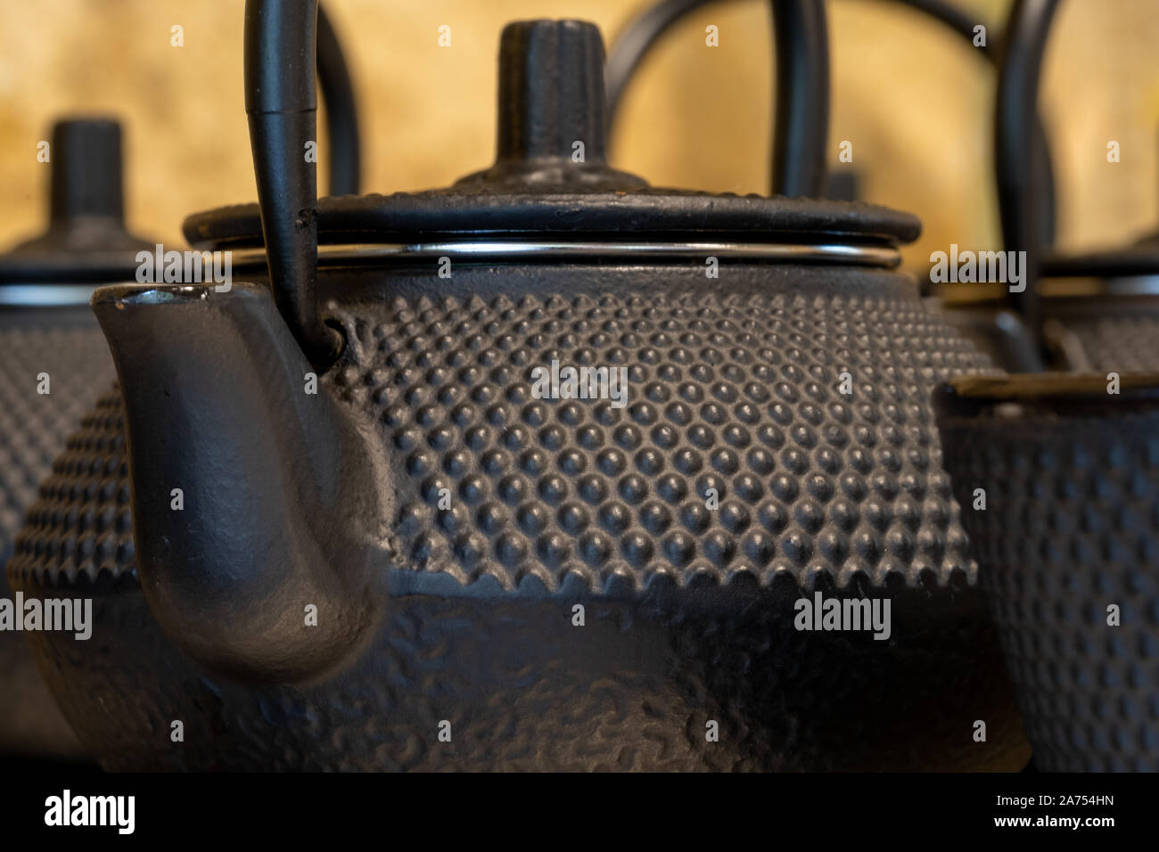 Close up of black textured cast iron Asian style tea pots with handles and matching cups. Stock Photo
