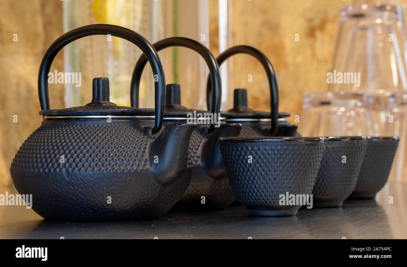 Close up of black textured cast iron Asian style tea pots with handles