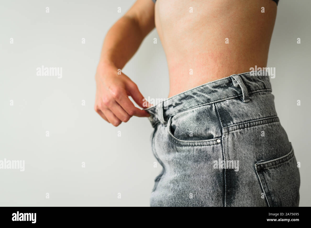 Woman belly after dieting in oversized pants. Skinny fat concept. Stretch marks Stock Photo