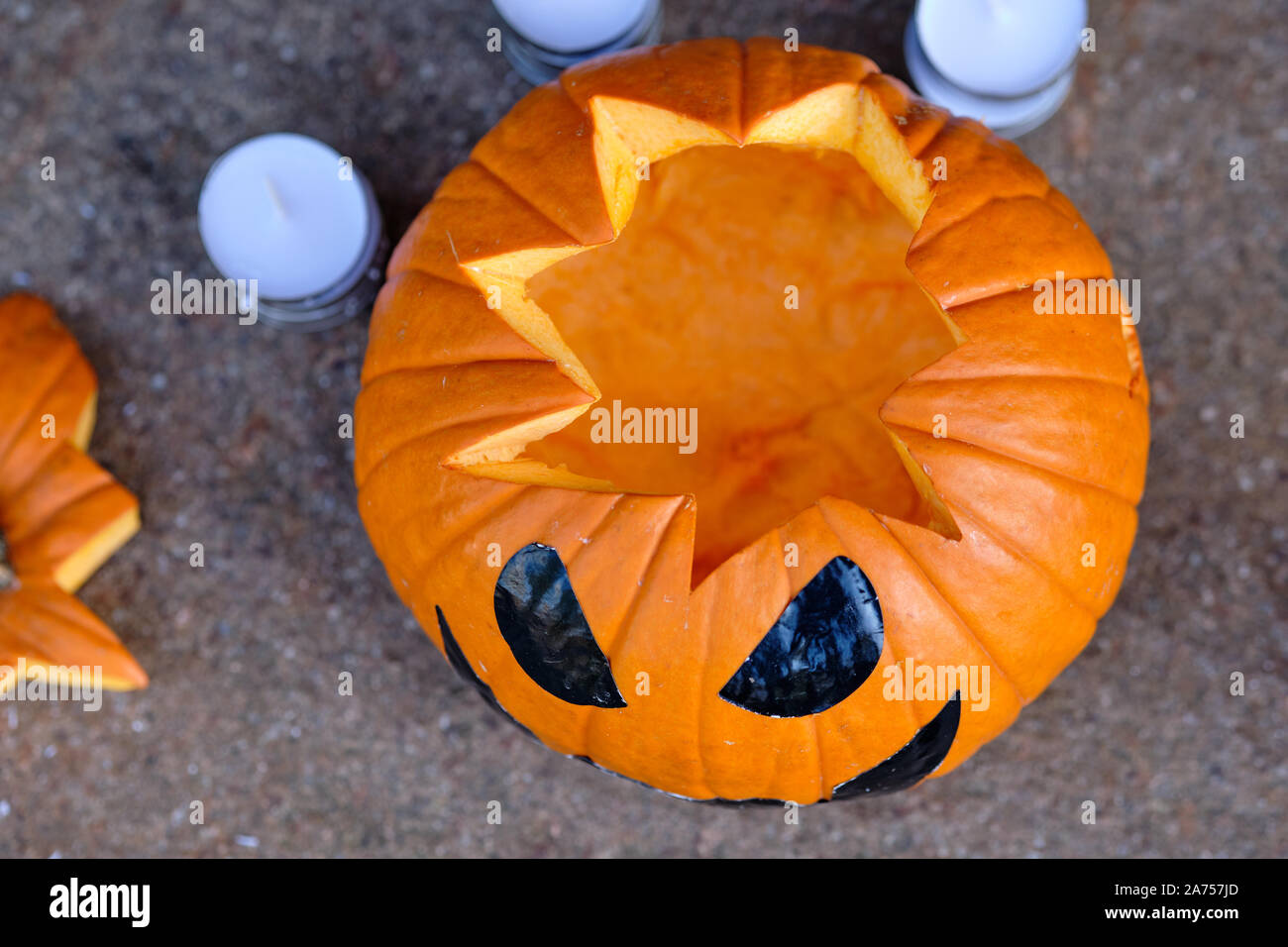 Smiling orange Halloween pumpkin lying on the ground together with some tea lights in the background. Seen in Germany, Bavaria, in October. Stock Photo