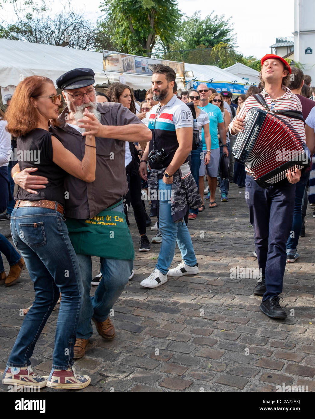 A couple dances to the chansonnier's song at the fete de vendanges below Sacre Coeur in Paris's Montmartre neighborhood. Stock Photo