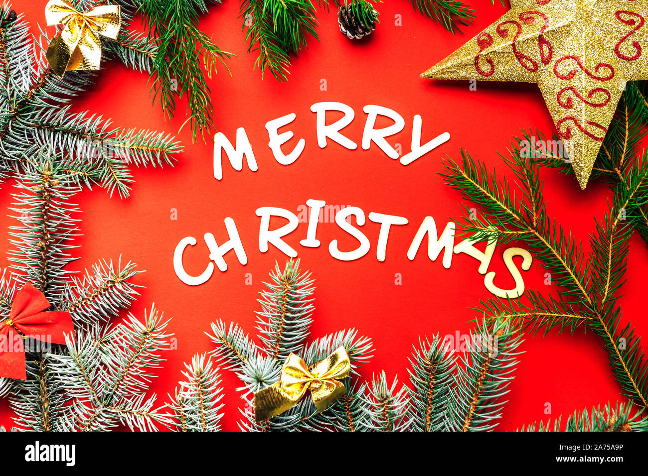 Wooden letters of Merry Christmas words on red background flat lay