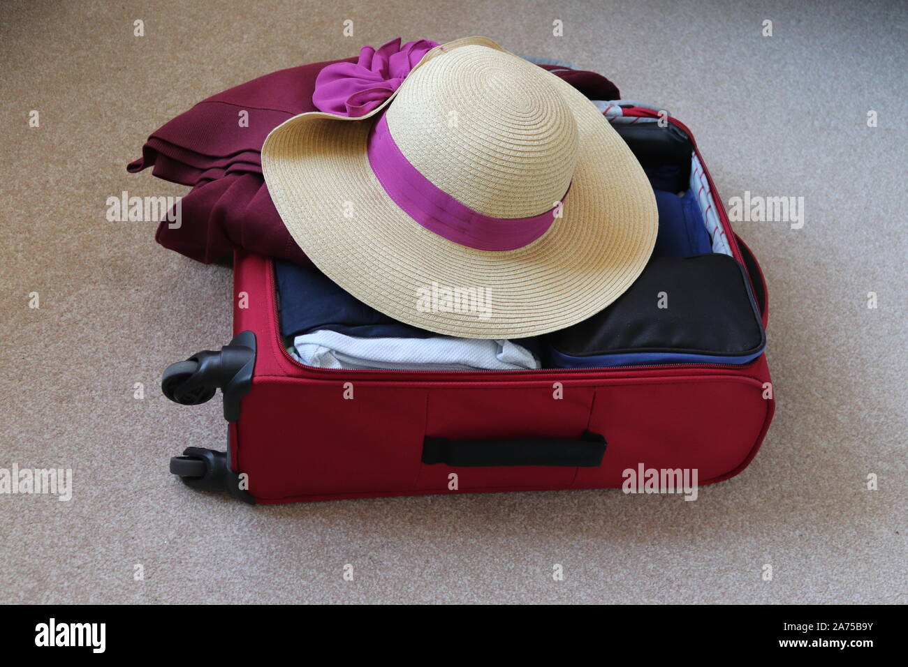 Hand luggage case packed for a holiday, clothing and a hat for summer