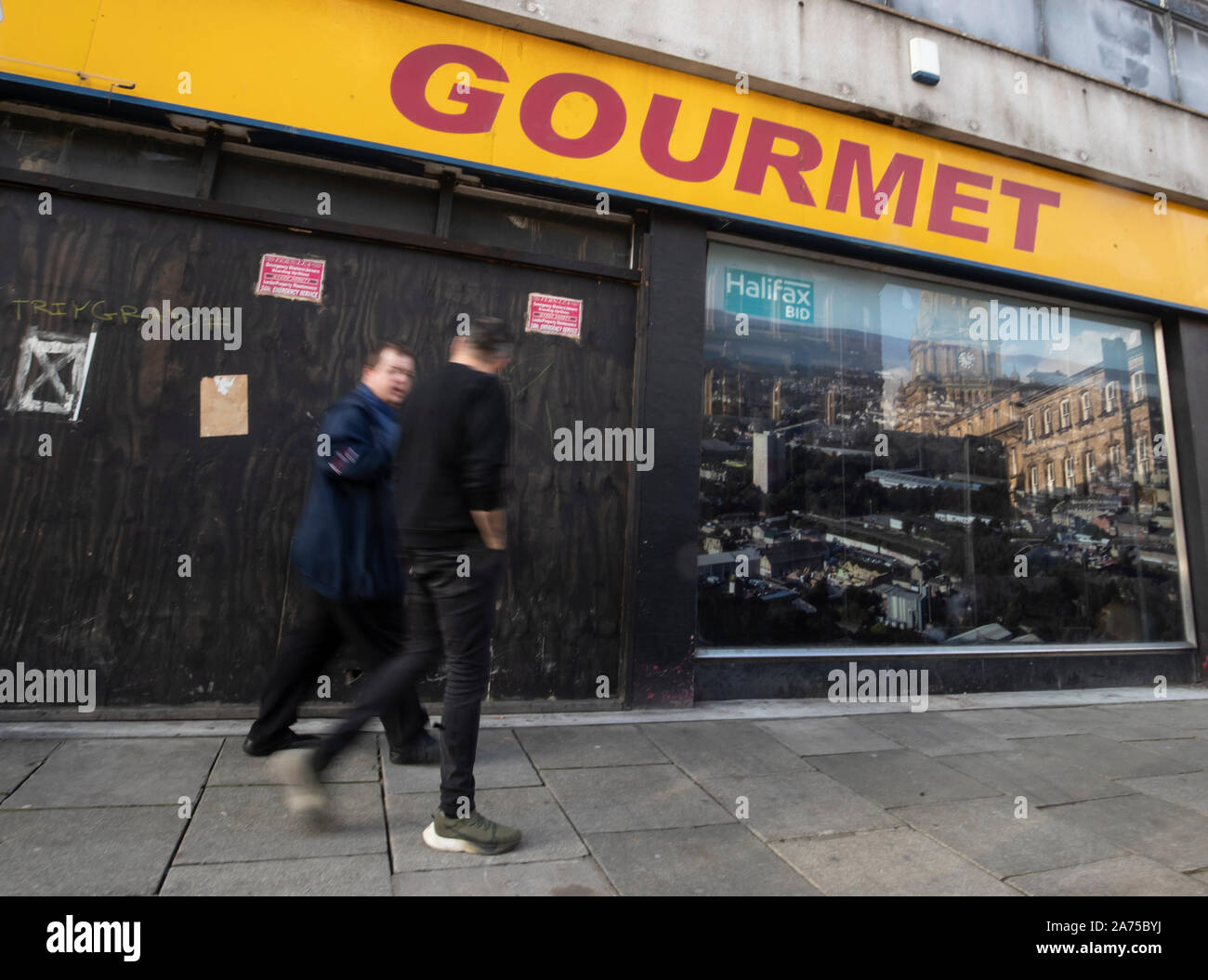 Men walk past a closed shop in Halifax in Yorkshire, as a think tank says the Conservatives will have to target traditional Labour voters from regional towns in order to win the general election. PA Photo. Picture date: Wednesday October 30, 2019. The Conservatives will have to target traditional Labour voters from regional towns such as Workington in order to win the Christmas general election, according to a think tank. The group urged the party to target towns including Halifax, Warrington, Wigan and Workington in order to gain these key regional seats. Photo credit should read: Danny Lawso Stock Photo