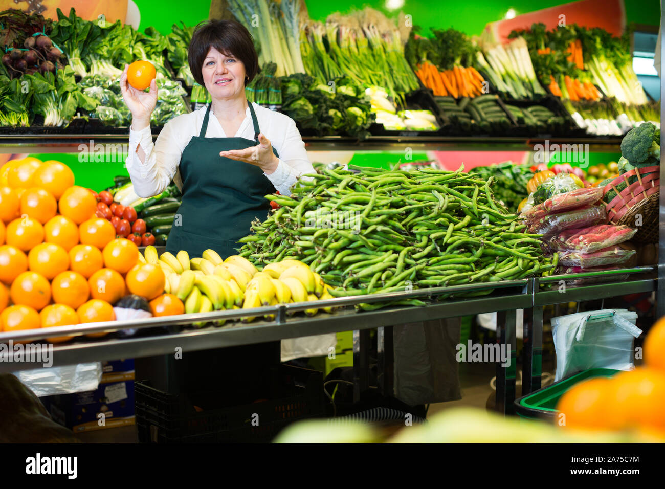 Mature woman offering fresh vegetables and fruits on the market Stock ...