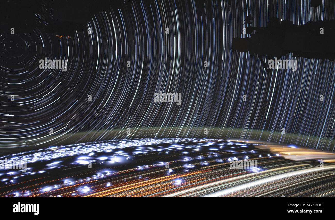 This image of star trails, photographed in July 2019, was compiled from time-lapse photography taken by NASA astronaut Christina Koch from aboard the International Space Station. This composite image was constructed from more than 400 individual photos taken over about 11 minutes as the station traveled from Namibia toward the Red Sea. The image includes many natural and artificial lights that an astronaut may see during an orbit at night. On the ground, stationary features like cities appear as pale yellow-white dotted streaks, with each dot marking another frame captured. Many of the thinner Stock Photo