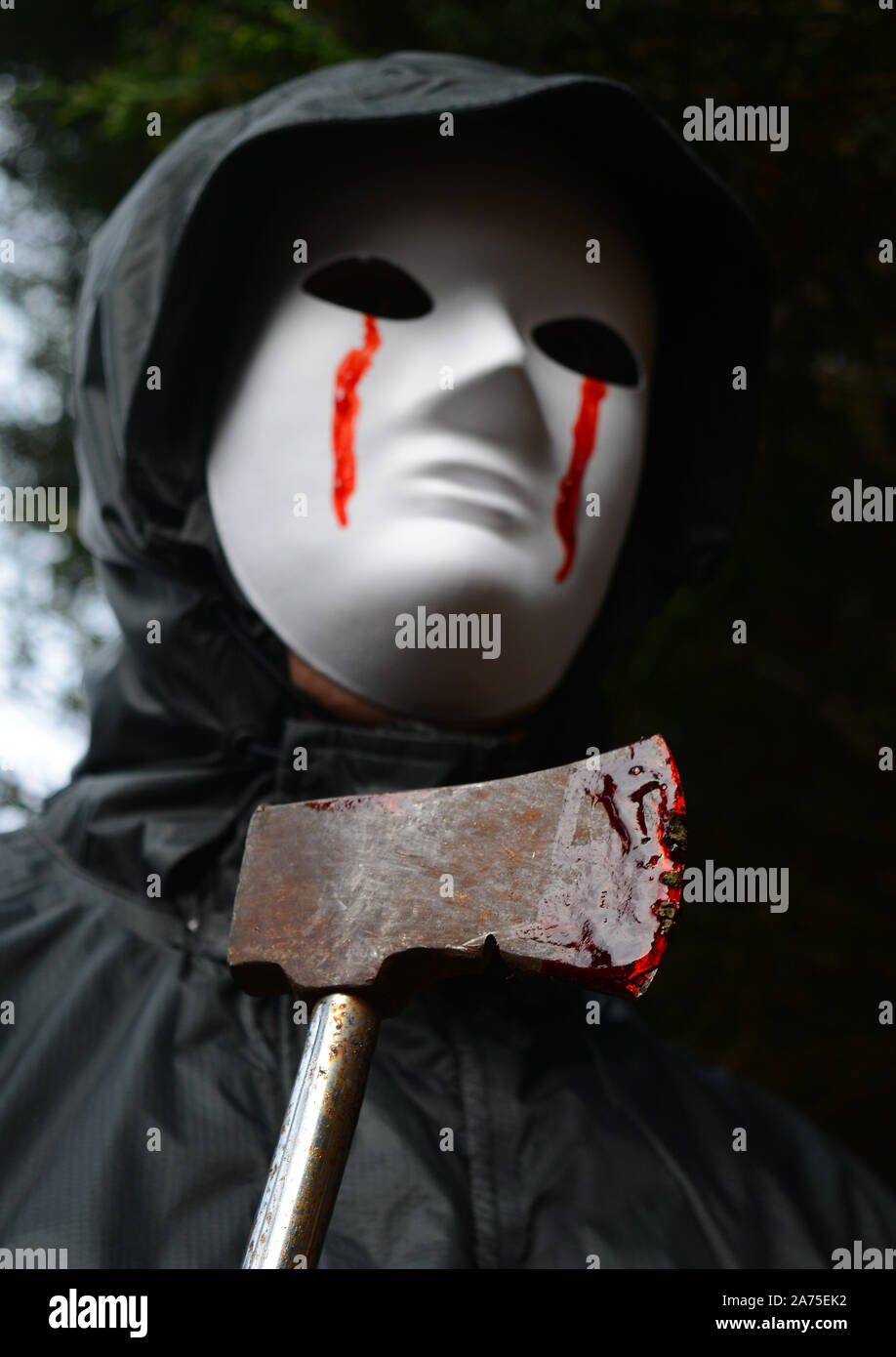 Masked attacker with a blood stained axe Stock Photo