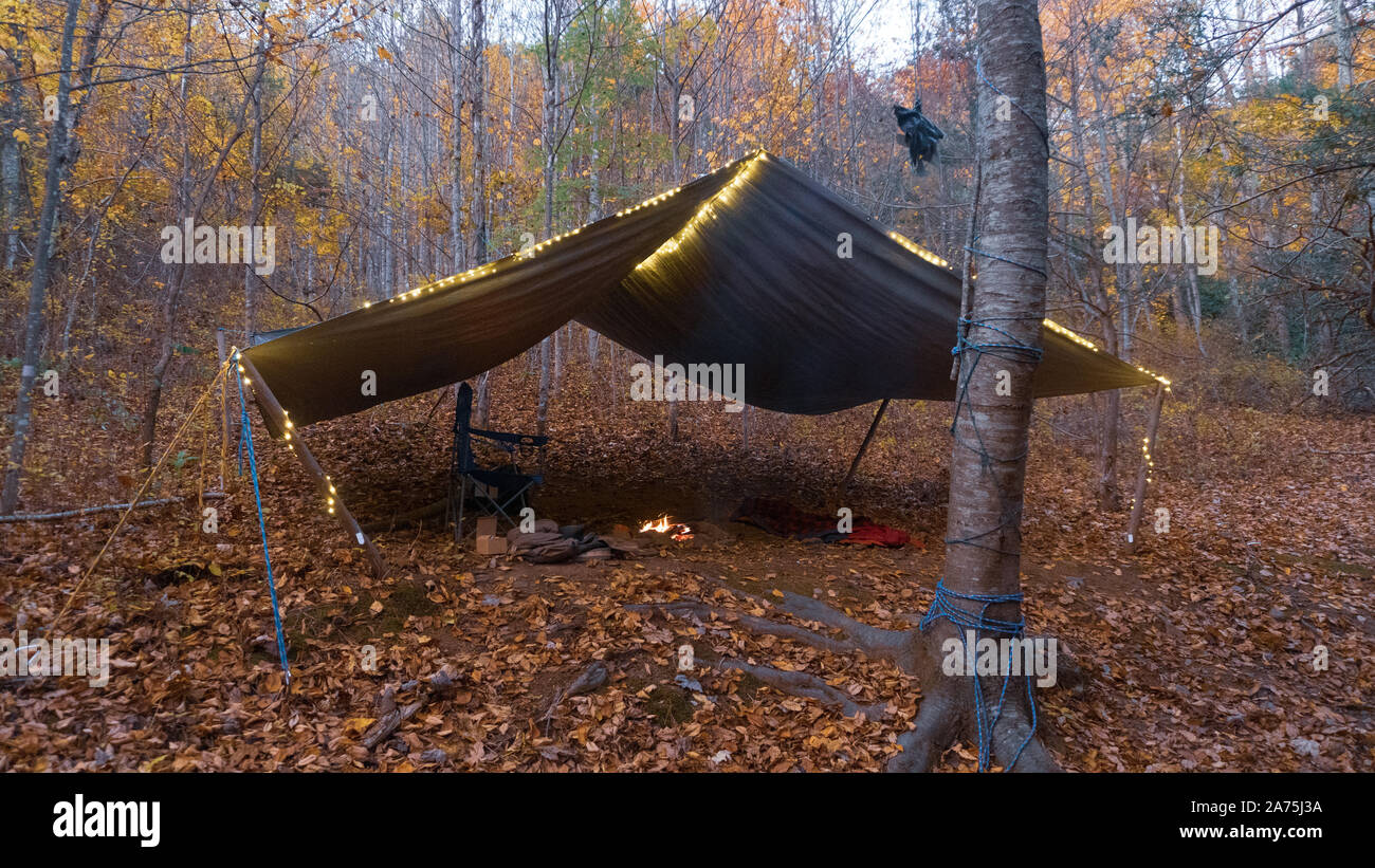 Primitive Tarp Shelter with campfire and fairy lights. Survival Bushcraft setup in the Blue Ridge Mountains near Asheville. Stock Photo