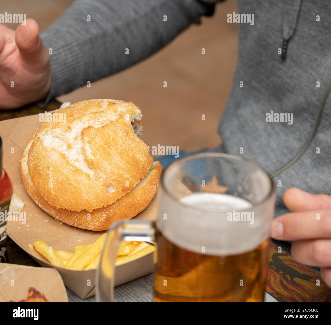 Man eating a burger drinking beer in a restaurant Stock Photo