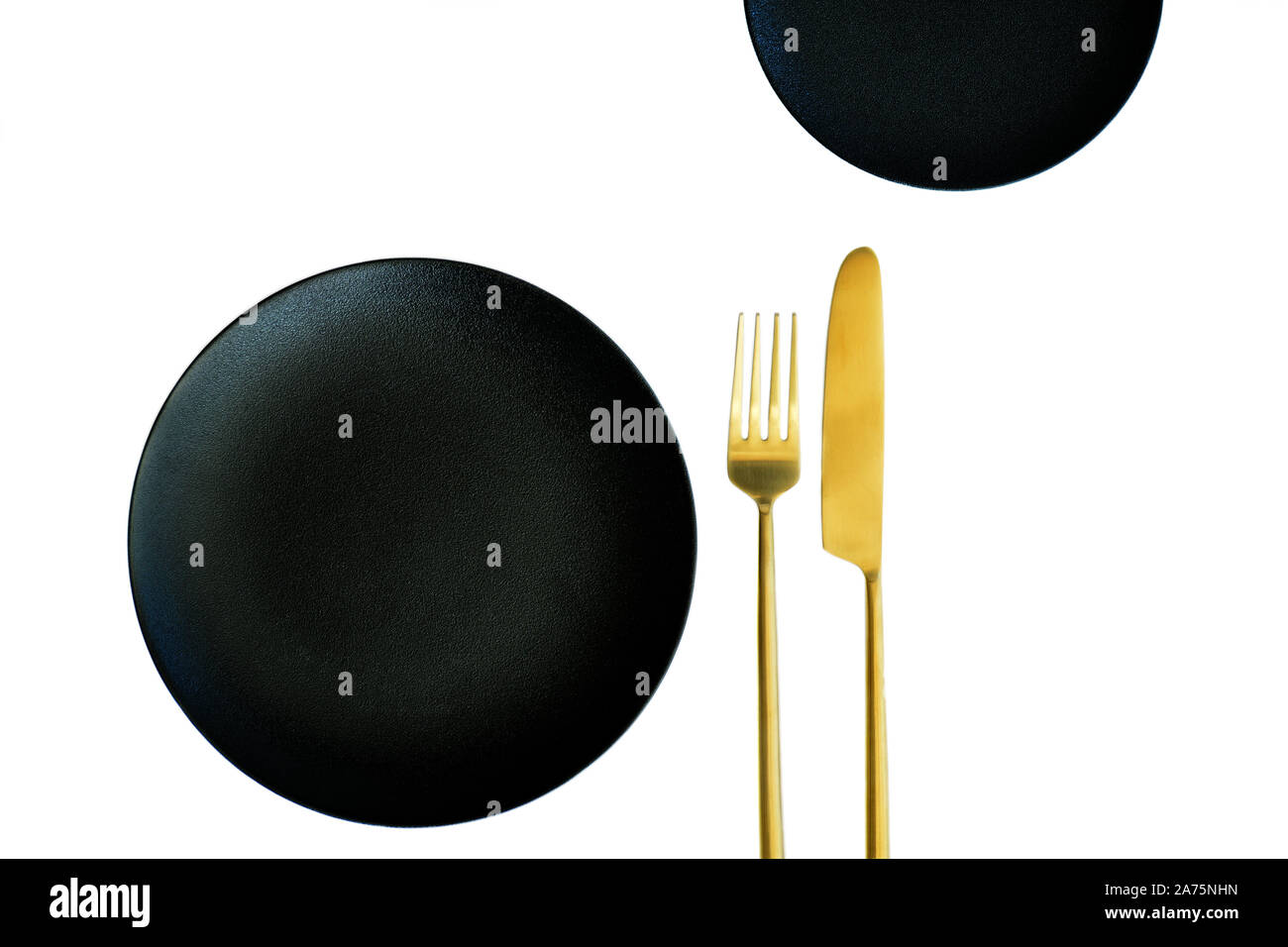 Black textured plates with gold knife and fork isolated on white ...