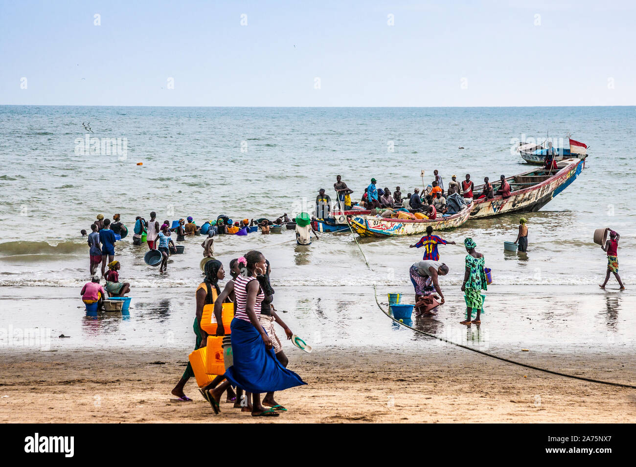 Women wait with buckets for the men to unload their catch in Tanji Fishing Village in The Gambia. Stock Photo