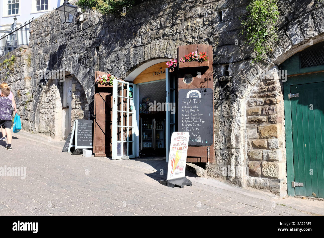 Tenby, Wales. July 25, 2018. holidaymakers walk past a shop and cafe in the arches on Penniless Cove hill beside the harbour at Tenby in South Wales, Stock Photo