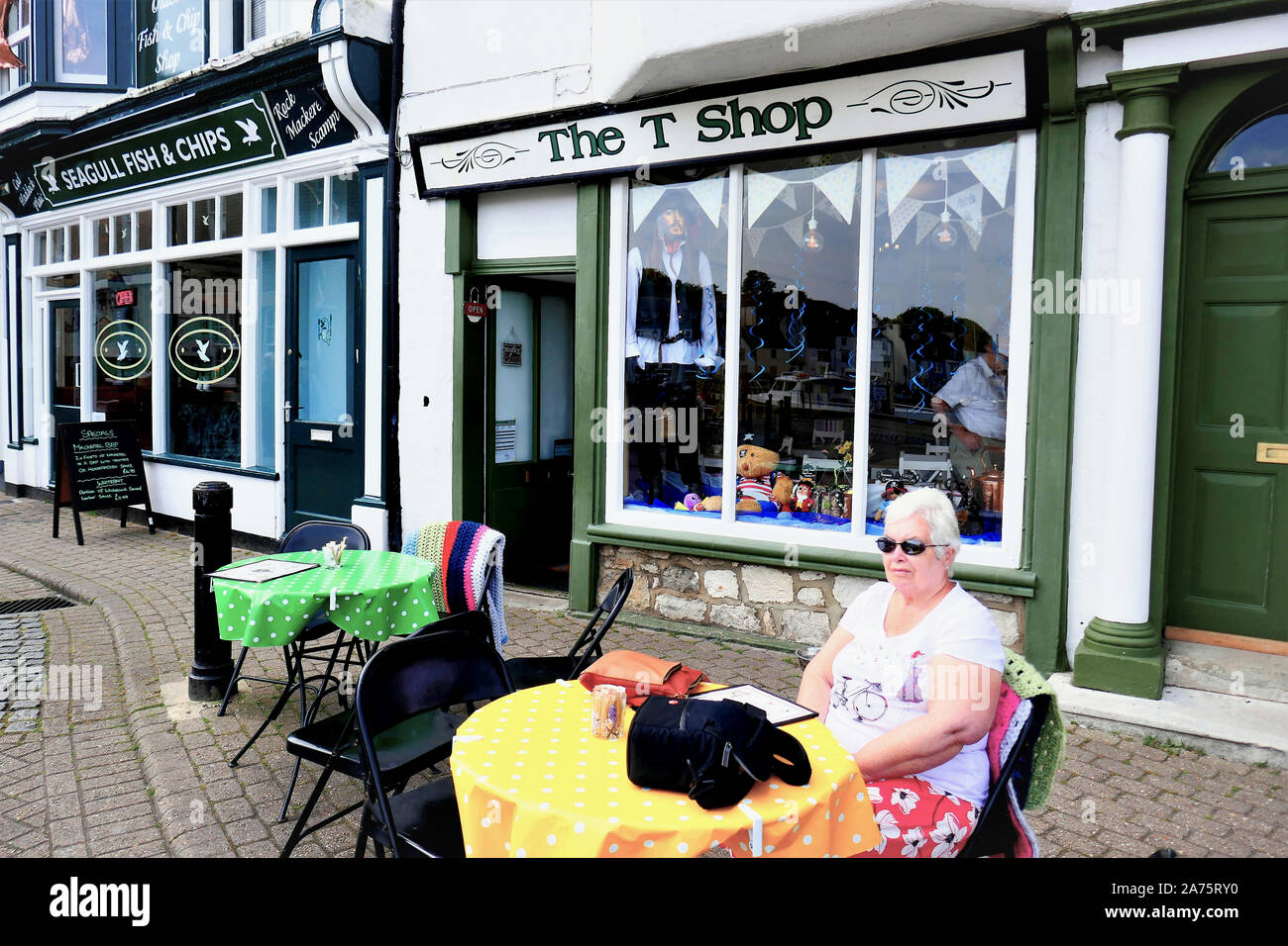 Weymouth, Dorset, UK. May 18, 2018. A senior lady sitting alfresco outside the T shop on the habour at Weymouth in Dorset, UK. Stock Photo